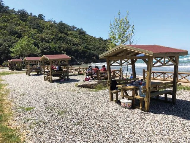 Çakıl plajda ahşap kamelya ve piknik üniteleri